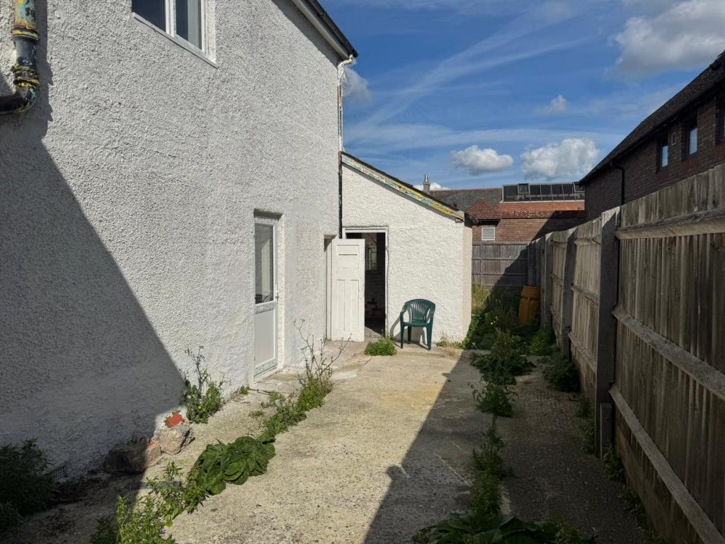 Lot: 58 - FREEHOLD TAKEAWAY UNIT WITH TWO-BEDROOM LIVING ACCOMMODATION - Side view of building and patio area